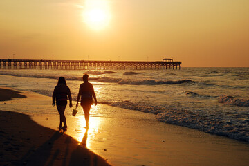 Two women take a sunrise stroll along the shore in Myrtle Beach, South Carolina
