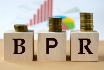 BPR - abbreviation on wooden balls on a background of coins and graphics.