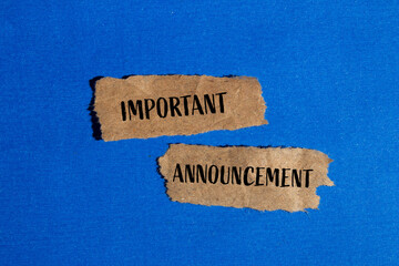 Important announcement words written on torn brown paper pieces with blue background. Conceptual...