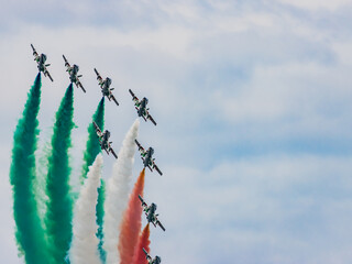 Air show, group of planes performing aerobatics, airplanes in flight in the blue sky, Italy.