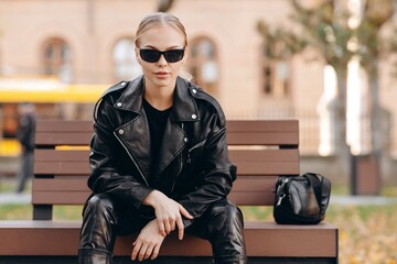 Stylish young woman with black sunglasses on her eyes is looking away, wearing a black t-shirt, a...