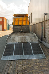 back of a low loader trailer parked on the street next to a factory hall