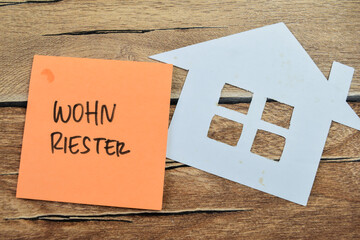 Concept of Wohn Riester in Language Germany write on sticky notes isolated on Wooden Table.