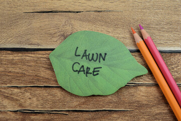 Concept of Lawn Care write on sticky notes isolated on Wooden Table.