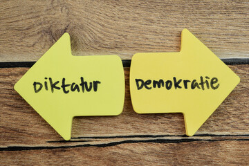 Concept of Diktatur or Demokratie in Language Germany write on sticky notes isolated on Wooden...