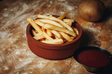 Golden French Fries in a Ceramic Bowl With Ketchup on a Textured Table