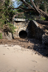 Large culvert pipe under road for management of rainwater and flash floods, stone facing, leading...