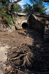 Large culvert pipe under road for management of rainwater and flash floods, stone facing, leading to sandy beach, Maui, Hawaii
