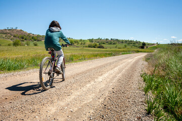 A young boy is riding a bike down a dirt road