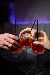 A woman holds a cocktail in her hand, with her fingers wrapped around the glass