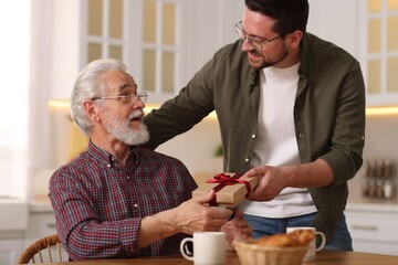 Son giving gift box to his dad at home