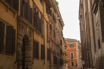 Obraz premium Horizontal overall plan photo of buildings with the bright blue sky background on the ancient street in Italy in the city of Verona, Veneto region. Veronese beautiful streets in the summer