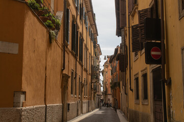 Fototapeta premium Horizontal overall plan photo of buildings with the bright blue sky background on the ancient street in Italy in the city of Verona, Veneto region. Veronese beautiful streets in the summer