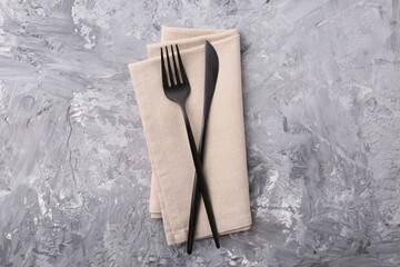 Elegant cutlery and kitchen towel on grey textured table, top view