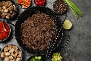 Wok with noodles, chicken and other products on grey table, flat lay