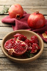 Fresh pomegranates and green leaves on wooden table