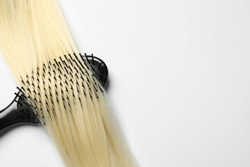 Stylish brush with blonde hair strand on white background, top view