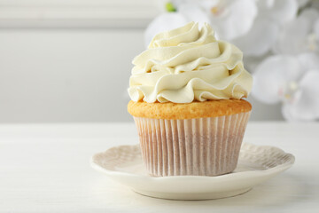 Tasty vanilla cupcake with cream on white table, closeup
