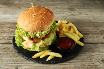 Burger with delicious patty, french fries and sauce on wooden table