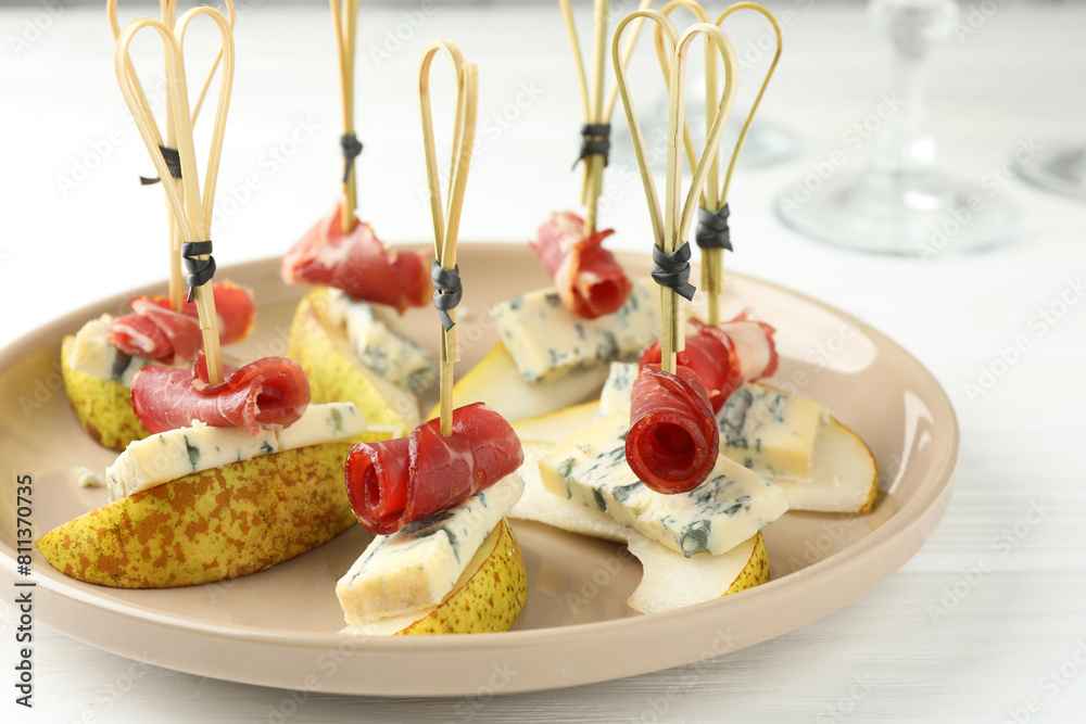 Wall mural Tasty canapes with pears, blue cheese and prosciutto on white wooden table, closeup