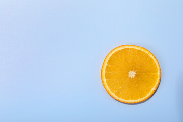 Slice of juicy orange on light blue background, top view. Space for text