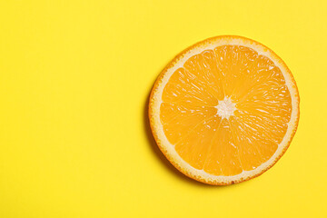 Slice of juicy orange on yellow background, top view. Space for text