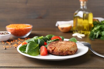 Tasty fried vegetarian cutlet served with spinach and tomato on wooden table