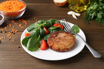 Tasty fried vegetarian cutlet served with spinach and tomato on wooden table
