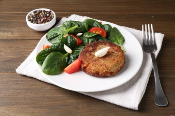 Tasty vegetarian cutlet served with vegetables on wooden table