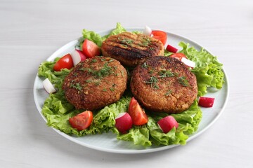 Delicious vegetarian cutlets and vegetables on white table, closeup
