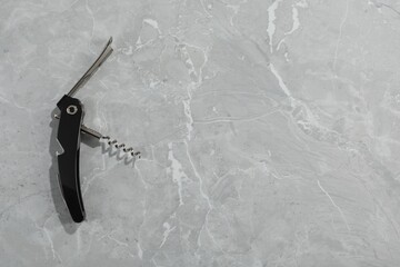 One corkscrew (sommelier knife) on grey marble table, top view. Space for text