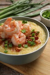 Fresh tasty shrimps, bacon, grits and green onion in bowl on table, closeup