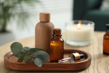 Aromatherapy. Bottles of essential oil and eucalyptus leaves on wooden table