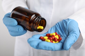 Woman holding many antibiotic pills and bottle, closeup. Medicinal treatment