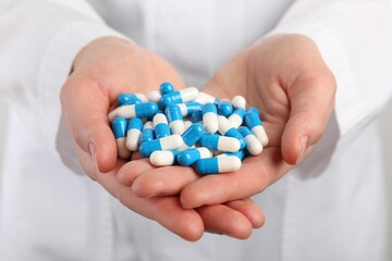 Woman holding many antibiotic pills, closeup. Medicinal treatment