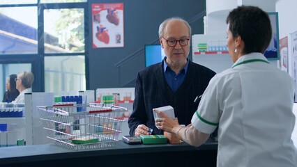 Aged shopper arriving at drugstore checkout counter after finding needed pharmacological products,...