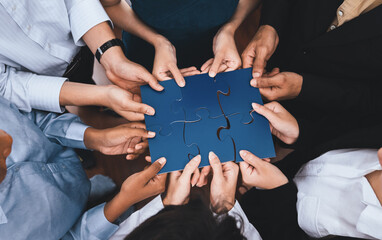 Diverse corporate officer workers collaborate in office, connecting puzzle pieces to represent...