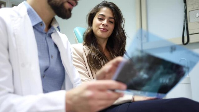 Young dentist explaining the treatment to his female patient