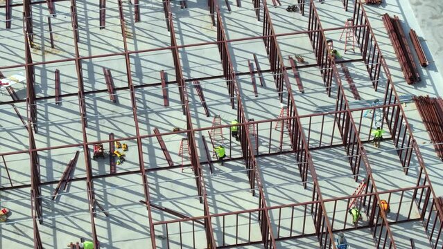 Development of commercial housing in USA. Construction works on monolithic frame. Large building site with scattered workers and equipment. Real estate market.