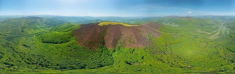 drone flies over a spring Carpathian peak with an interesting phenomenon - the mountain forest on the mountain is green up to a certain height, and above without leaves