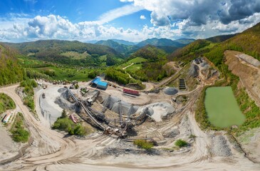 Carpathian Mountains of Ukraine, a quarry where granite sandstone is mined for the production of building materials, powerful trucks and conveyors load gravel - video from a drone