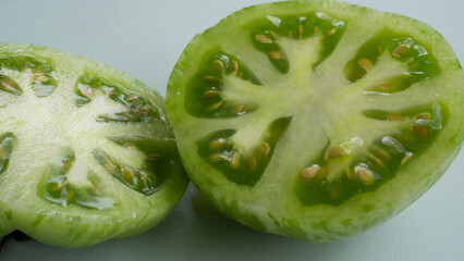 Green gourmet tomato cut up in two large slices. Captured in a highly detailed close up. Green...