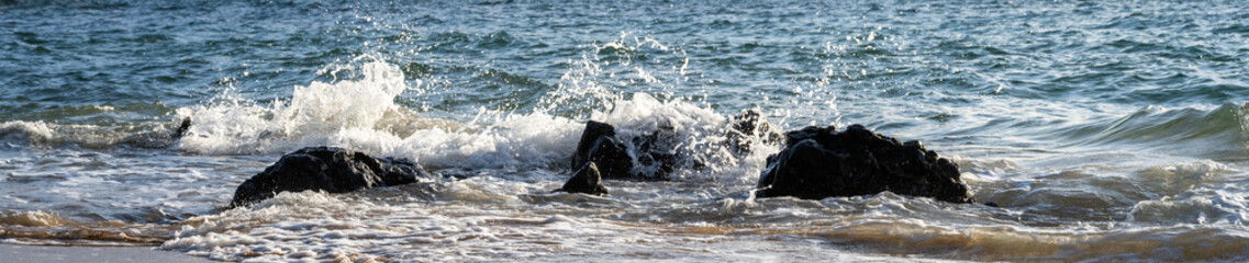 Fototapeta premium Point of black lava rock extending into the Pacific Ocean, wave action at Kamaole Beach Park II at sunset, Kihei, Maui, Hawaii 