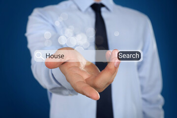 Real estate agent holding virtual search bar with word House on blue background, closeup