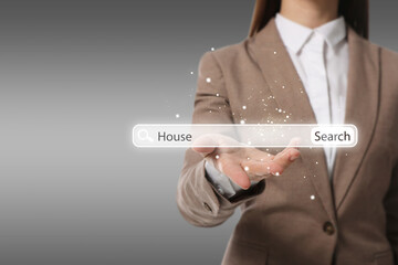 Real estate agent holding virtual search bar with word House on grey background, closeup. Space for...