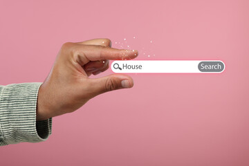 House hunting. Man holding virtual search bar on pink background, closeup