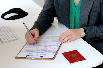 Top view close up of a woman filling out visa application documents with a Russian passport