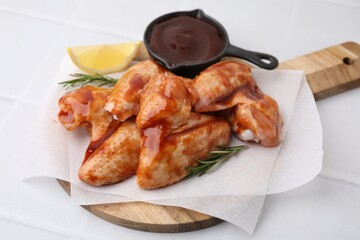 Raw chicken wings, rosemary, lemon and marinade on light tiled table, closeup