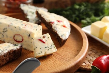 Tasty butter with dill, chili pepper and rye bread on table, closeup