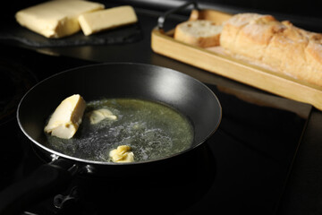 Melting butter in frying pan, dairy product and bread on black table